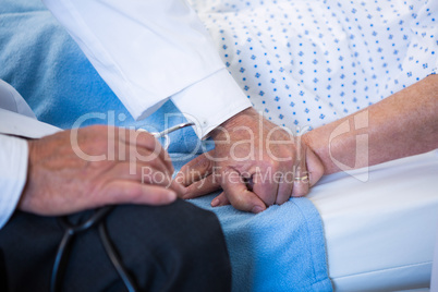 Mid-section of doctor consoling senior patient