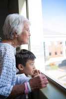 Senior patient and boy looking out from the window
