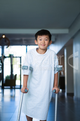 Boy patient walking with crutches in corridor