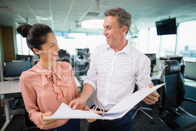 Smiling business colleagues discussing over clipboard at desk Smiling business colleagues discussing over clipboard at desk