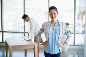 Portrait of smiling business executive standing with hands on hip