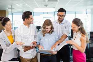 Business colleagues discussing over clipboard and digital tablet at desk in office