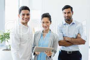 Smiling business colleagues discussing over digital tablet in office