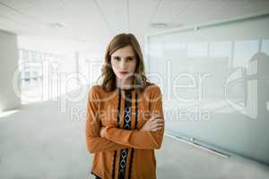 Business executive standing with arms crossed in office corridor