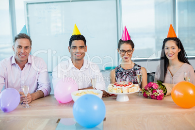Portrait of smiling colleagues celebrating birthday of woman
