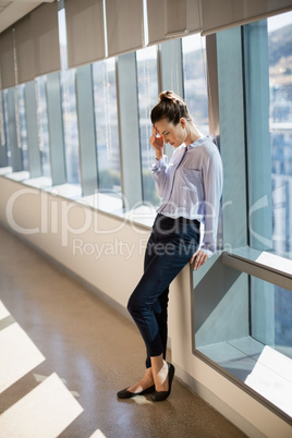 Tense female business executive leaning near window