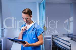 Smiling doctor writing on clipboard in ward