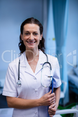 Portrait of female doctor standing with clipboard in ward