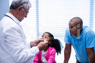Doctor interacting with patient while checking temperature on thermometer