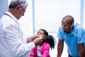 Doctor interacting with patient while checking temperature on thermometer