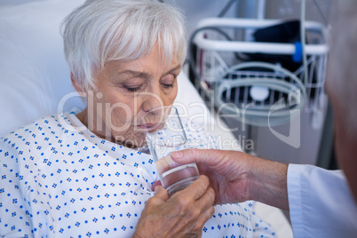 Doctor giving glass of water to seniorÃ?Â patient