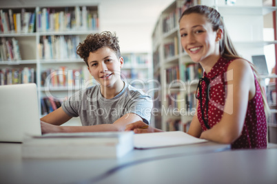 Portrait of happy classmates doing homework in library