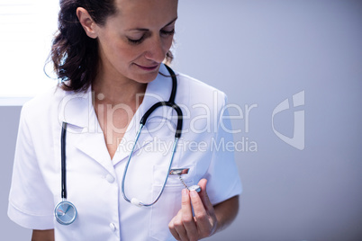 Female doctor checking time on pocket watch