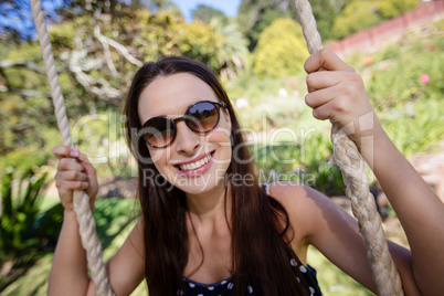 Smiling woman sitting on swing in park