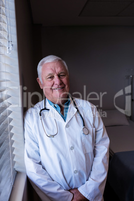 Portrait of male doctor standing near window in ward