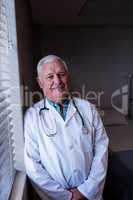 Portrait of male doctor standing near window in ward