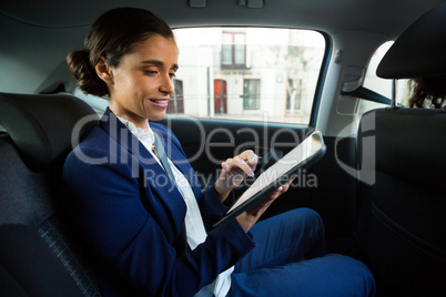Business executive using digital tablet in car