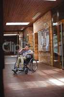 Disabled schoolboy on wheelchair in corridor at school