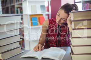 Attentive schoolgirl studying in library