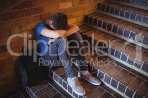 Sad schoolboy sitting alone on staircase