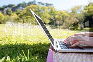Woman lying on mat and using laptop