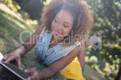 Woman lying on grass and using digital tablet