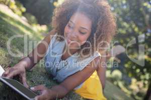 Woman lying on grass and using digital tablet