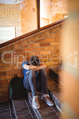 Portrait of schoolboy holding digital tablet and book near staircase