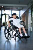 Disabled boy patient on wheelchair in hospital corridor