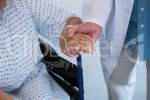 Doctor consoling senior patient on wheelchair at hospital