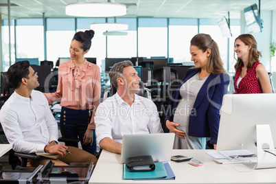 Business colleagues interacting with each other at desk in office