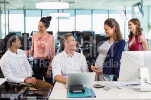 Business colleagues interacting with each other at desk in office