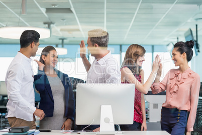 Business colleagues giving high five during meeting at desk in office