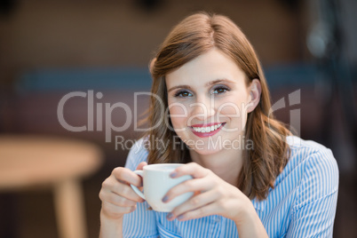 Smiling businesswoman drinking cup of coffee in office cafeteria