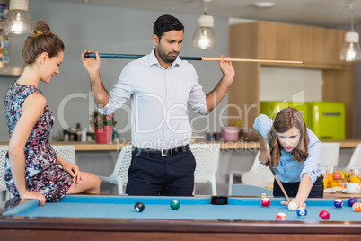 Business colleagues playing pool in office space