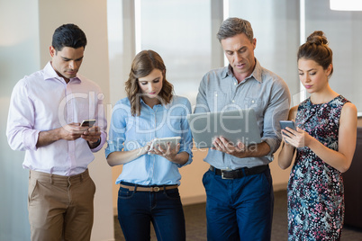 Business colleagues using mobile phone, digital tablet and laptop