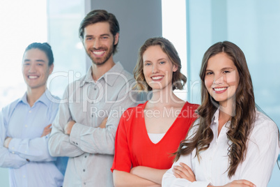 Business executives with arms crossed smiling while standing in office