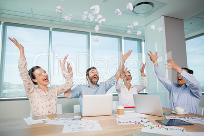 Happy business executives throwing crumpled paper in air