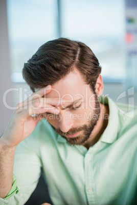 Tense business executive sitting with hand on forehead