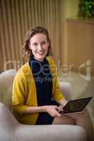Smiling business executive sitting with digital tablet on sofa