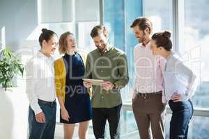 Smiling business executives discussing over digital tablet