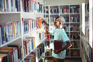 Schoolboy selecting book in library