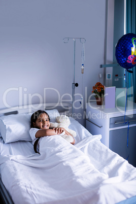 Portrait of patient relaxing on bed with teddy bear