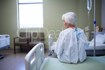 Rear-view of thoughtful senior patient sitting on bed