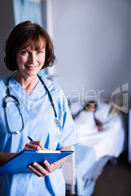 Smiling doctor writing on clipboard