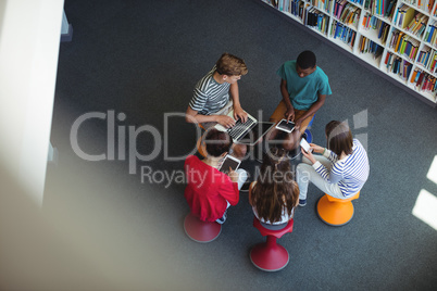 Students using laptop, mobile phone, digital tablet in library