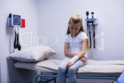 Girl with injured hand sitting on stretcher bed