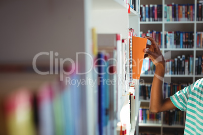 Schoolboy selecting book in library