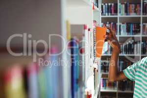 Schoolboy selecting book in library