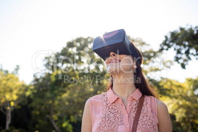 Smiling woman using a VR headset in the park